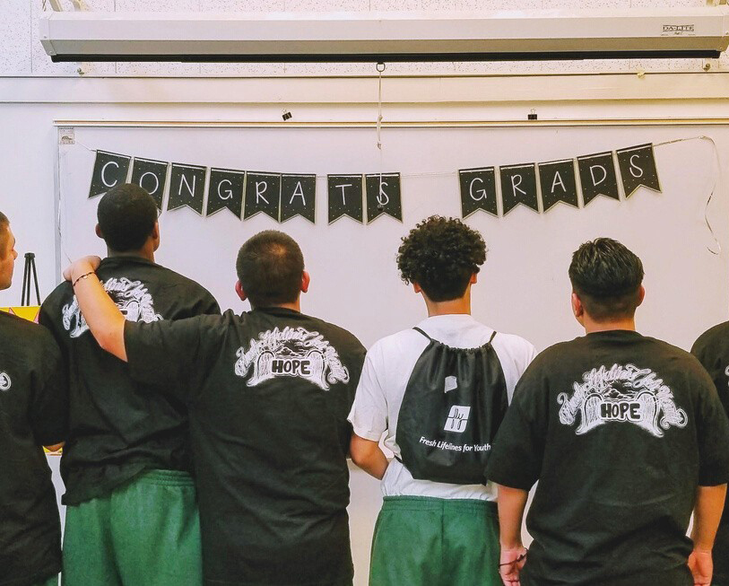 A group of teenagers standing in front of a "congrats grad" sign