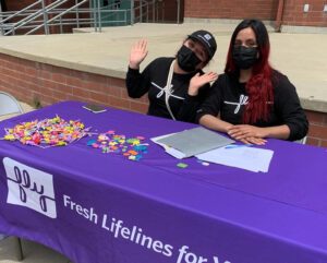 Two FLY Ambassadors sitting at a table handing out candy