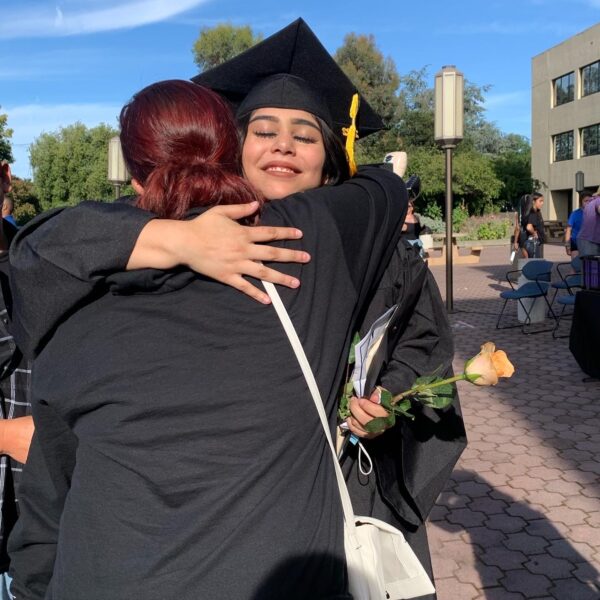 A mentor hugging a teenager celebrating their graduation