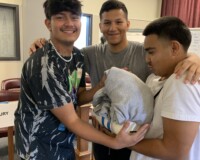 Group of friends smiling and holding a pillow