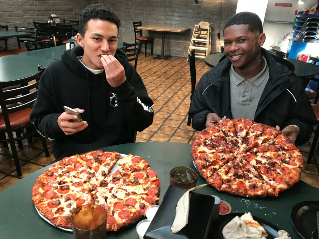 Two teenagers smiling and eating pizza