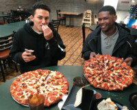 Two teenagers smiling and eating pizza