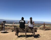 Two kids sitting on a park bench