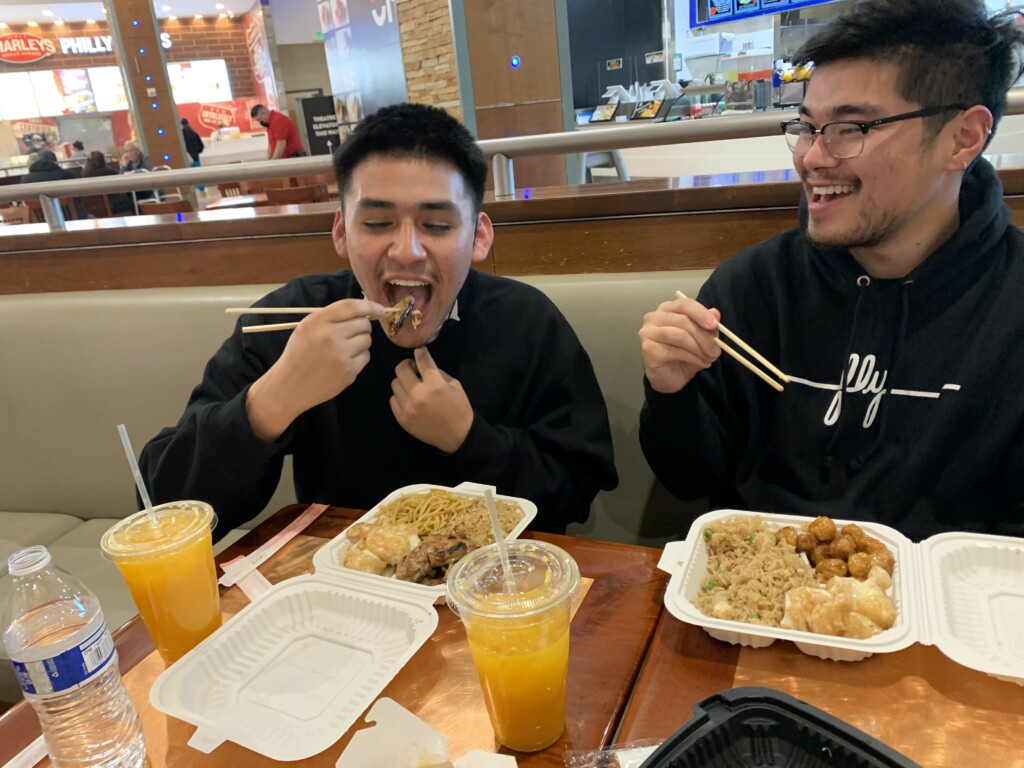 Two kids eating food out of a styrofoam box