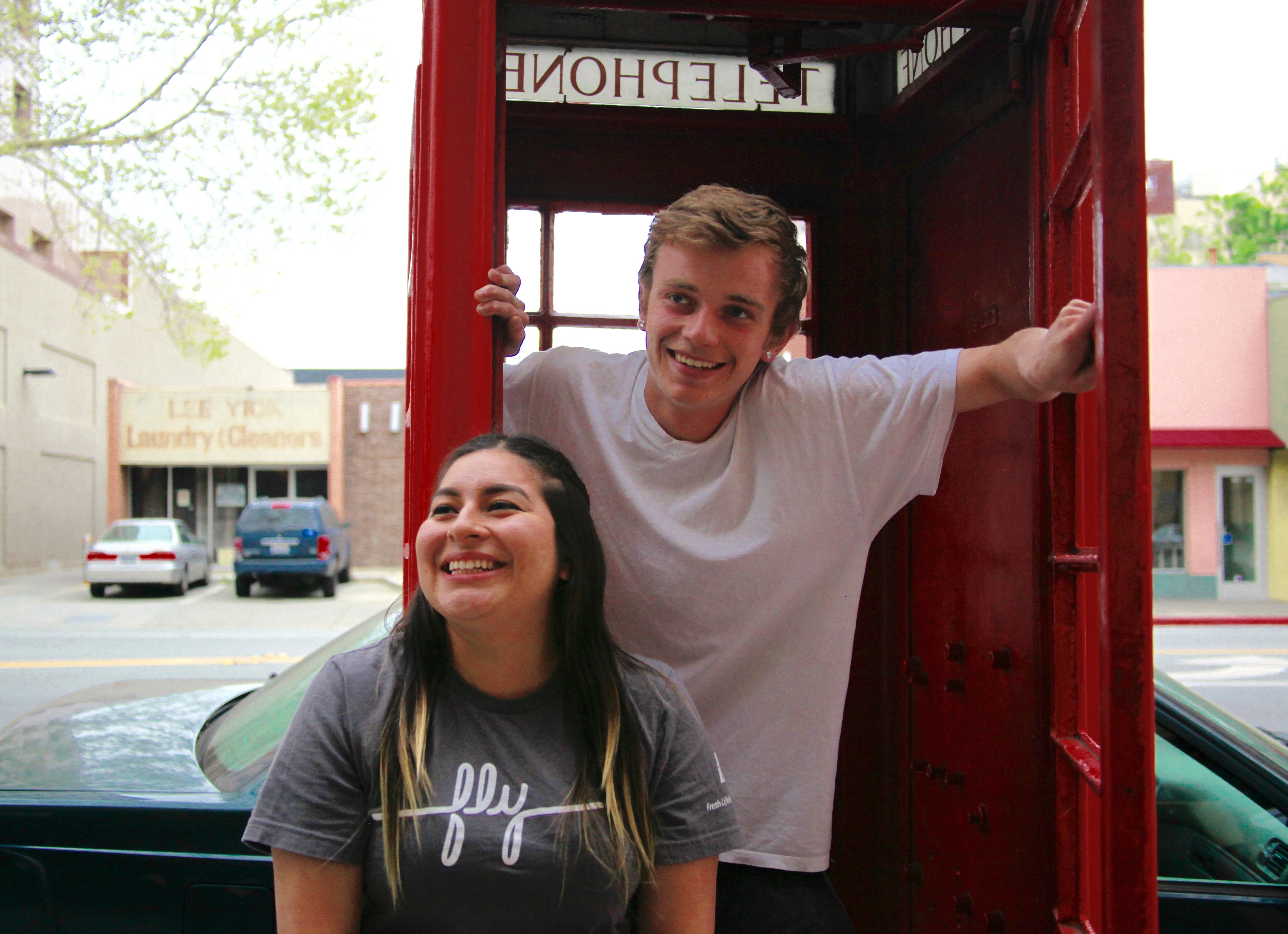 Two kids smiling in a telephone booth