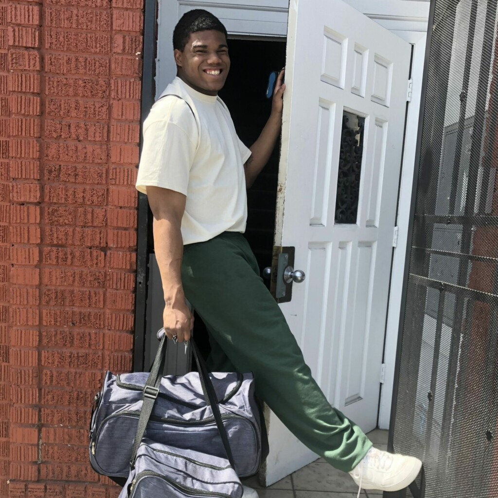 Young man carrying a bag through a door