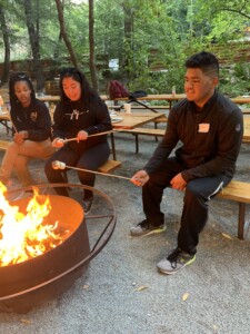 Group of people roasting s'mores over a campfire